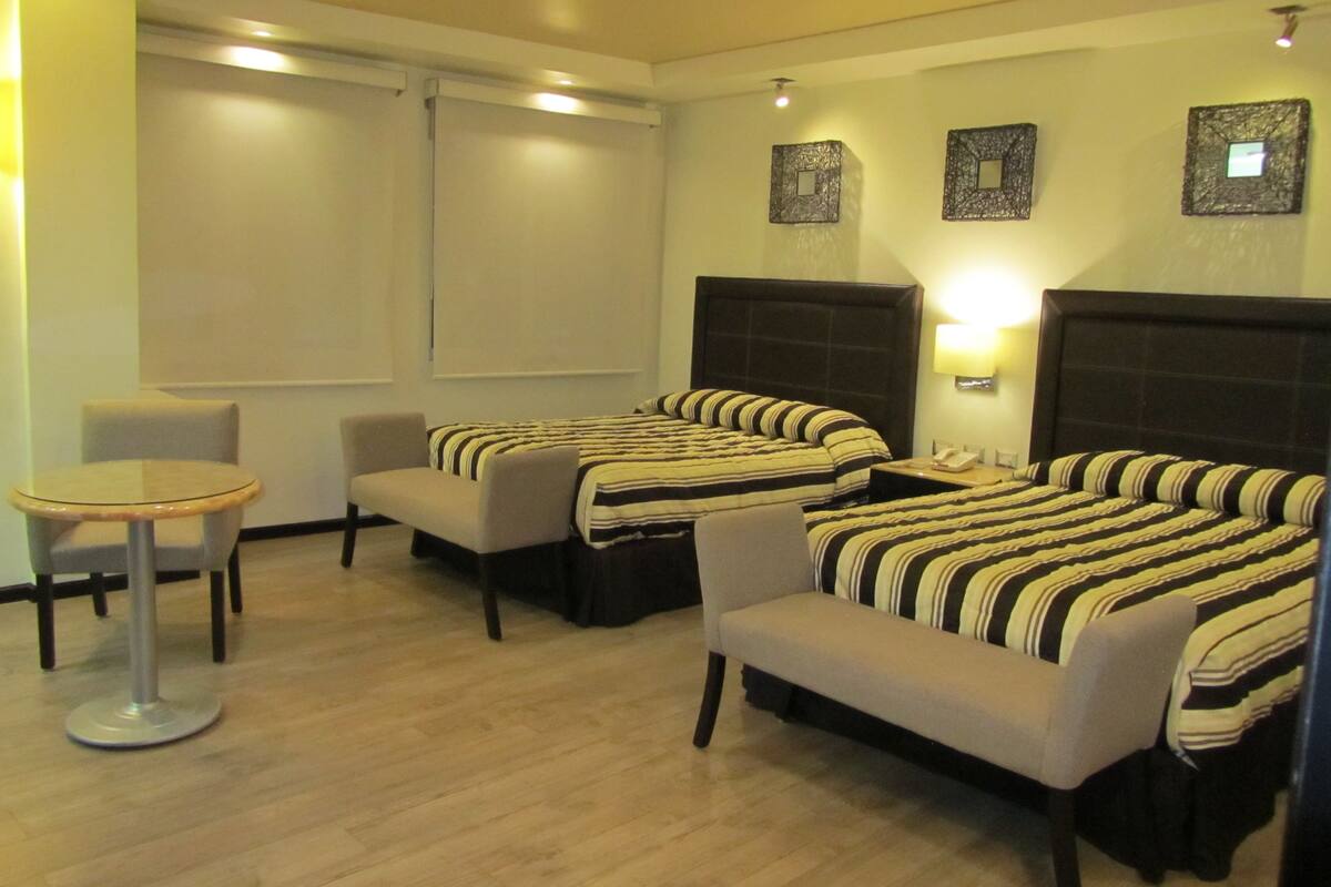 A hotel room with two beds, a small round table, and a chair.