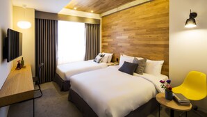 A hotel room with two beds, a wooden accent wall, a desk with a chair, a TV, and a bright yellow chair. - Hotel Denim (Seoul)