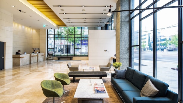 A modern lobby with a reception desk, seating area, and large windows offering a view of the street. - Hotel Denim (Seoul)