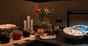 A buffet setup with various food items, a vase of flowers, and condiments on a counter. - Basur - das Schihotel am Arlberg (Flirsch)