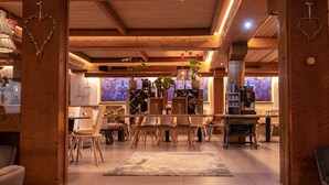 Un interior acogedor de madera con una zona de bar central, sillas de madera y una alfombra en el suelo.