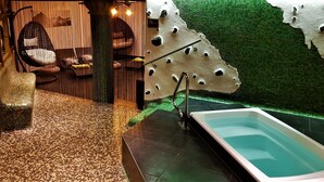 Un área de spa con bañera de hidromasaje, mosaicos y sillones colgantes.