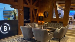 Un interior moderno con un amplio logotipo 'B', una zona de estar confortable, vigas de madera y adornos con forma de corazón.