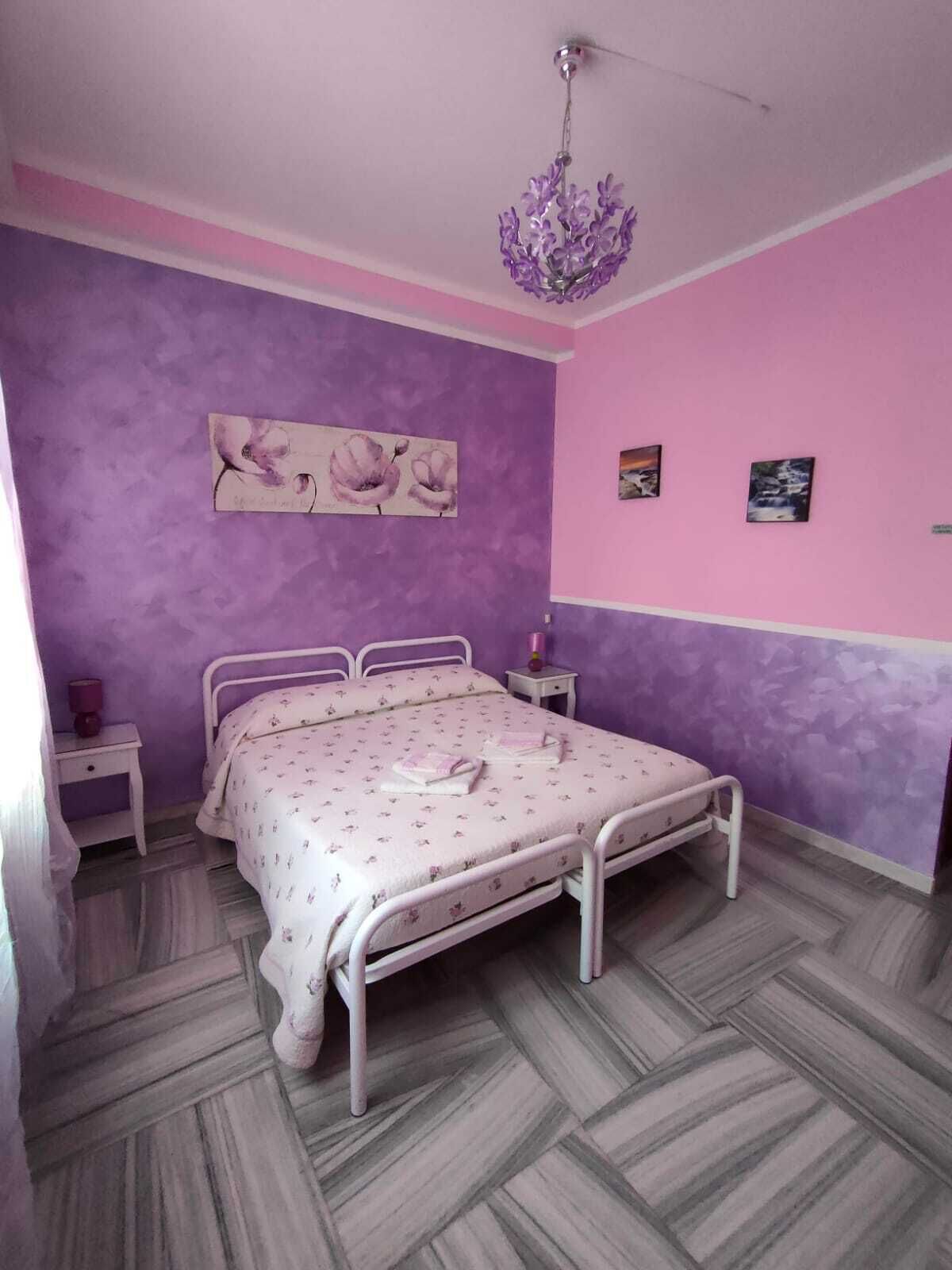 A bedroom with a bed, a nightstand, a lamp, and a chandelier.