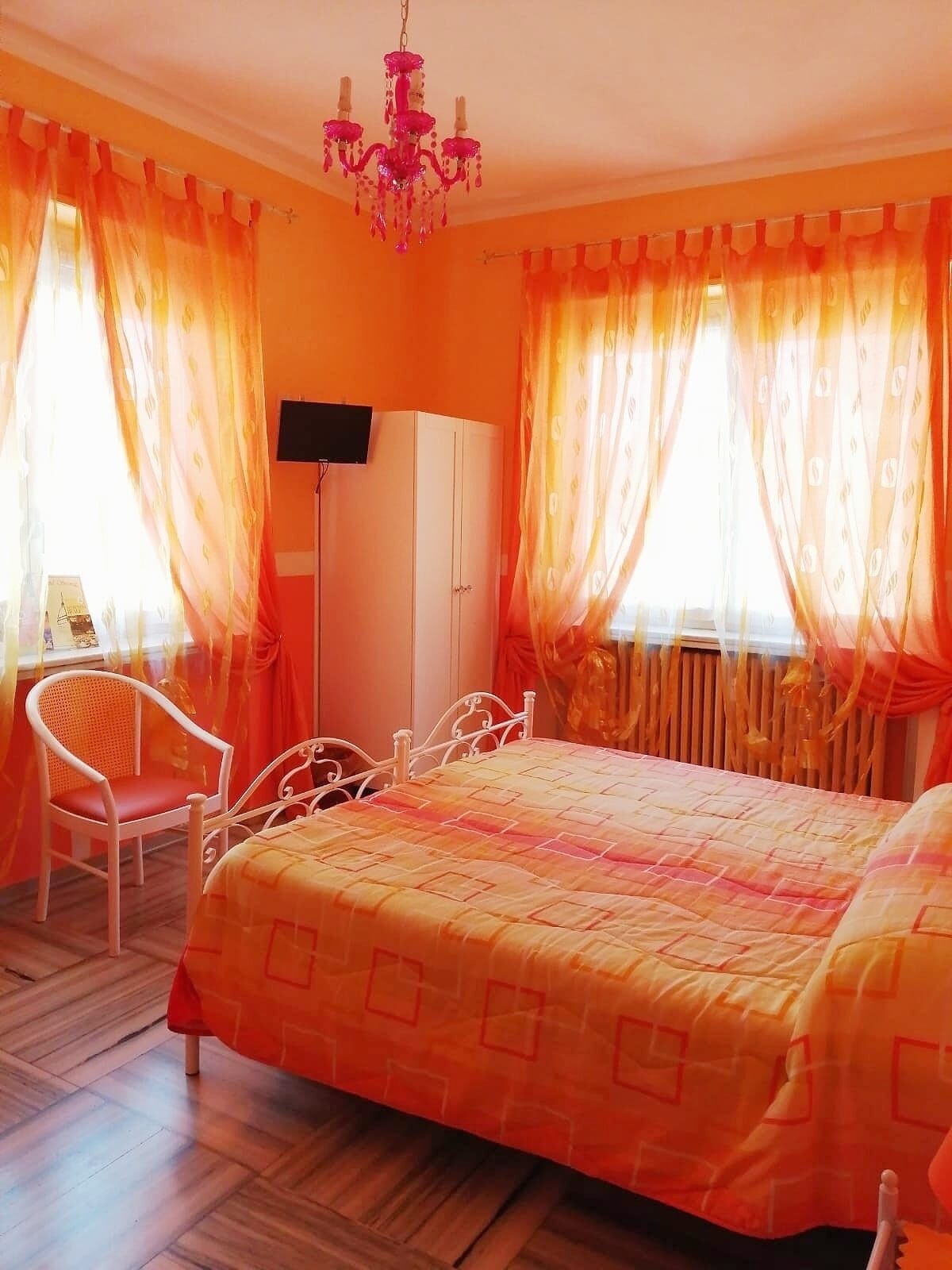 Un dormitorio con cama, una silla, un armario y una araña.