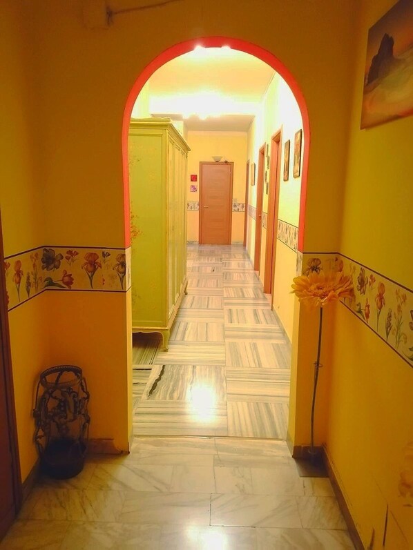 A hallway with a tiled floor and yellow walls, leading to a door at the end. - Hotel Serenella (Turin)