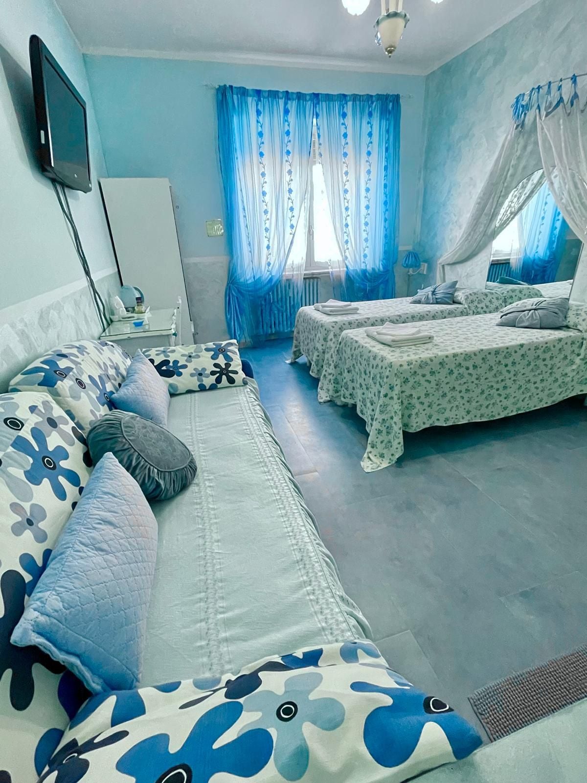 Una camera da letto con un divano letto, due letti singoli, una TV e un comodino.