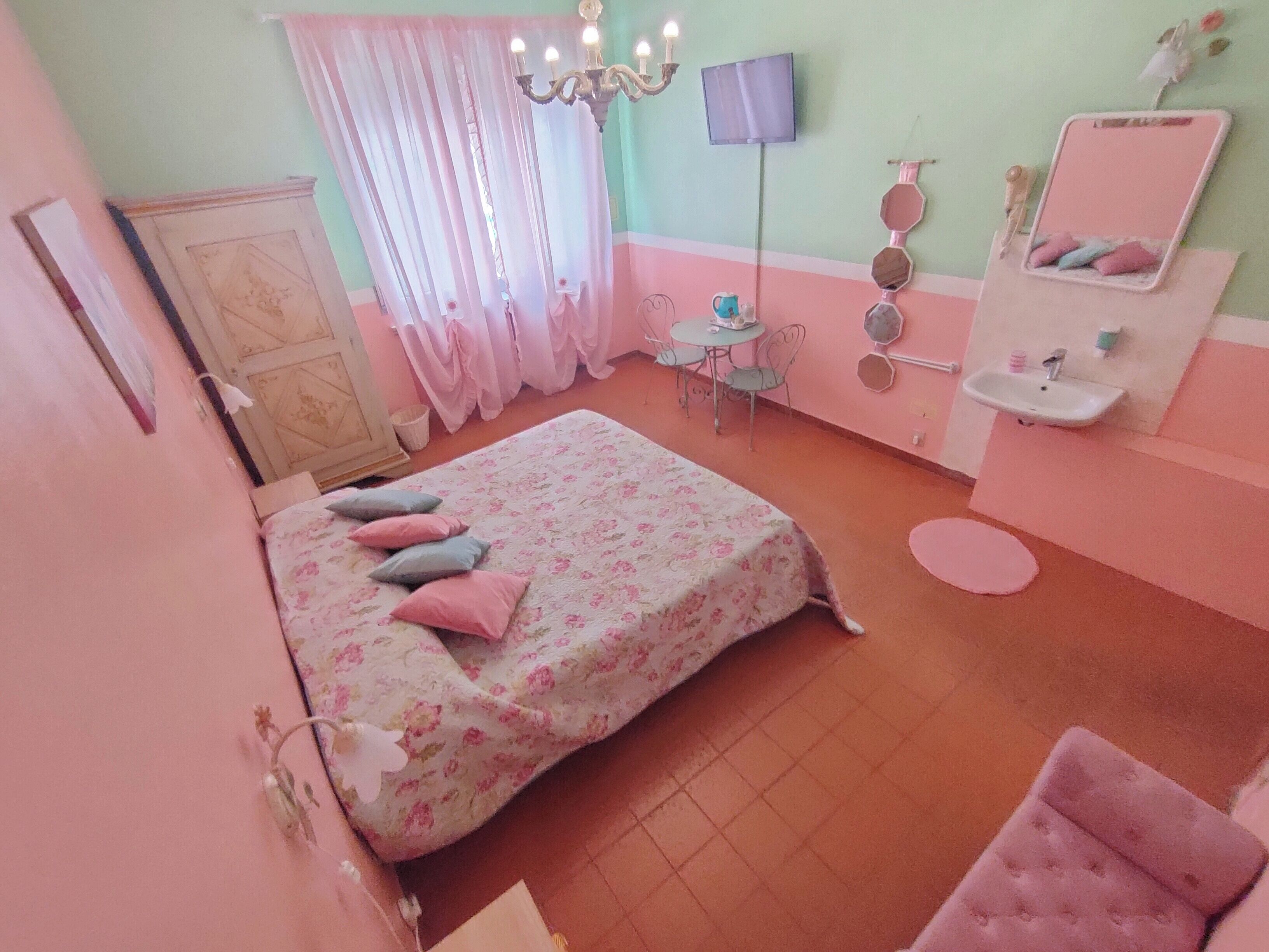 Quarto com cama, cômoda, penteadeira com espelho, mesinha e cadeira.