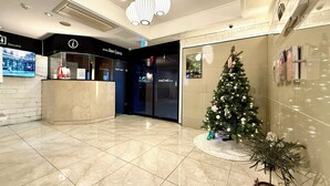 A hotel lobby with a reception desk, a Christmas tree, and a potted plant.