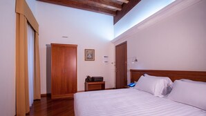 Ein Hotelzimmer mit einem großen Bett, einem Holzschrank und einem kleinen Nachttisch mit Lampe.