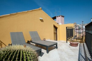 Una terraza en la azotea con dos sillones de descanso, una planta en maceta y un cactus.
