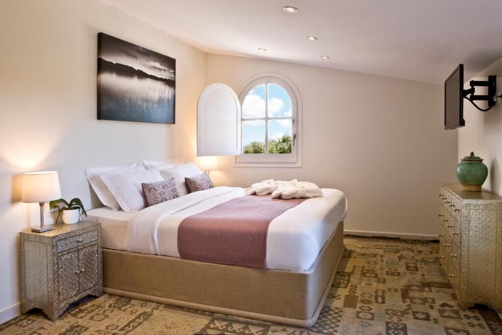Een netjes opgemaakt slaapkamer met een bed, nachtkastje, lamp en een decoratieve vaas.