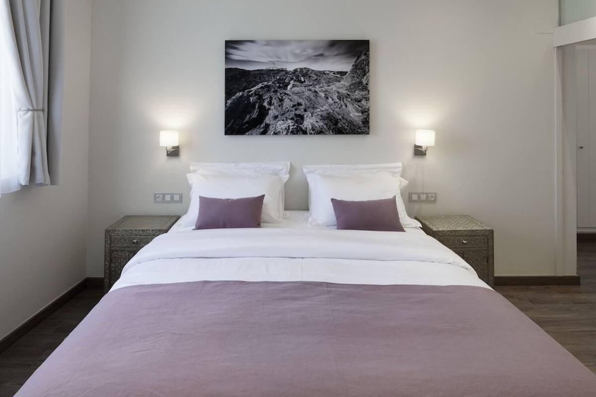 Ein Schlafzimmer mit einem großen Bett, zwei Nachttischen und einem Wandbild.