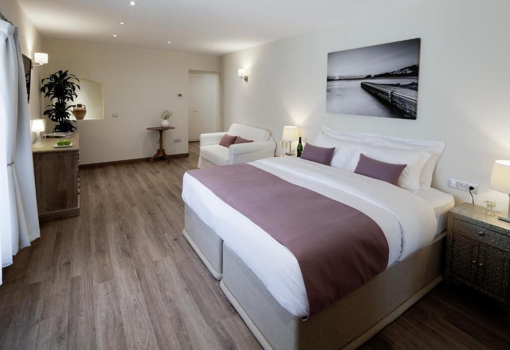 Habitación de hotel moderna con una cama grande, una pequeña zona de estar, un escritorio y vistas al mar.