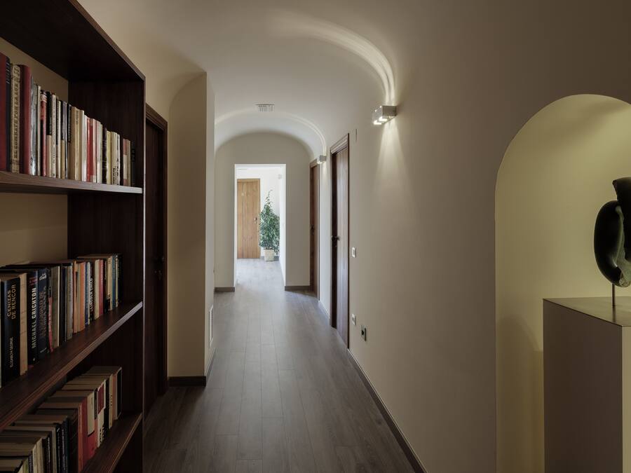 A hallway with bookshelves on the left and a modern sculpture on the right.