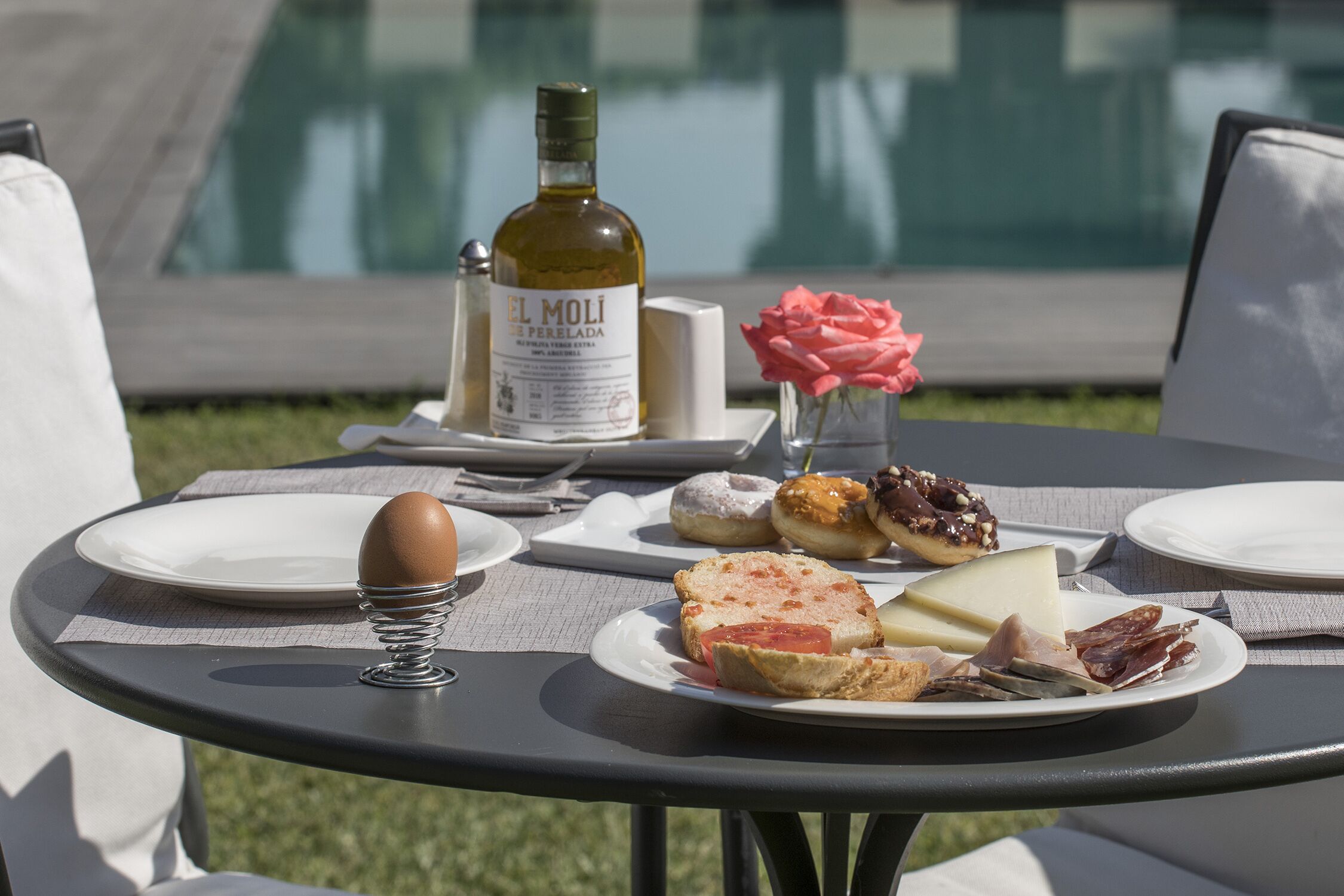A table with plates of food, a bottle of wine, and a vase with flowers.
