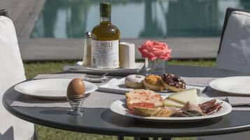 A table with plates of food, a bottle of wine, and a vase with flowers.