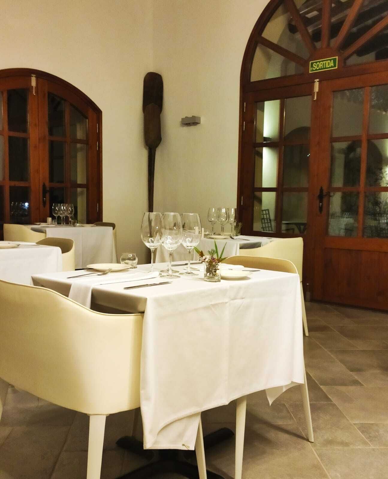 Un comedor con mesas dispuestas para una comida, una paleta de madera en la pared y un cartel que dice "SORTIDA".