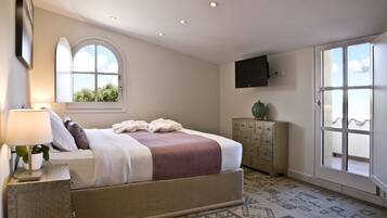 Een slaapkamer met een bed, nachtkastje, dressoir, raam en een televisie aan de muur.