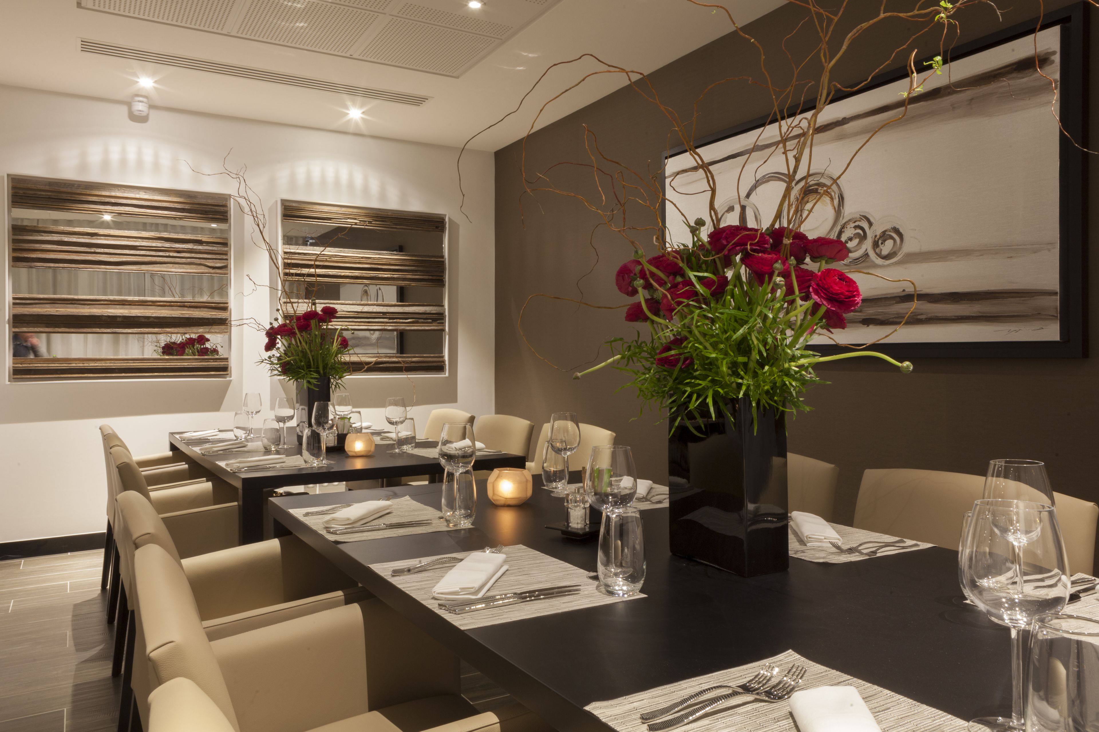 Un espace de restauration moderne, avec une longue table dressée pour un repas, entourée de chaises confortables.