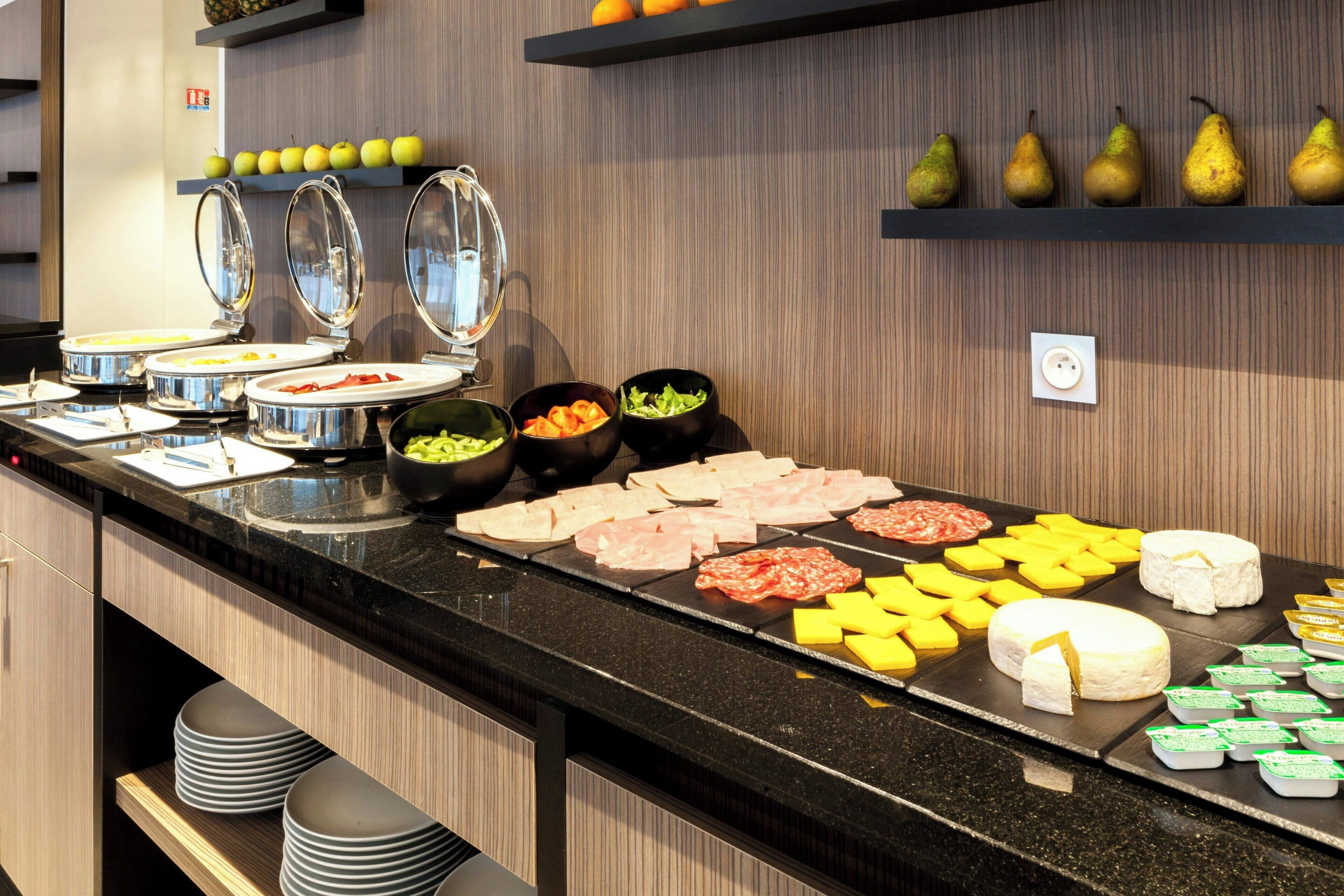 A buffet with various food items including meats, cheeses, and fruits.