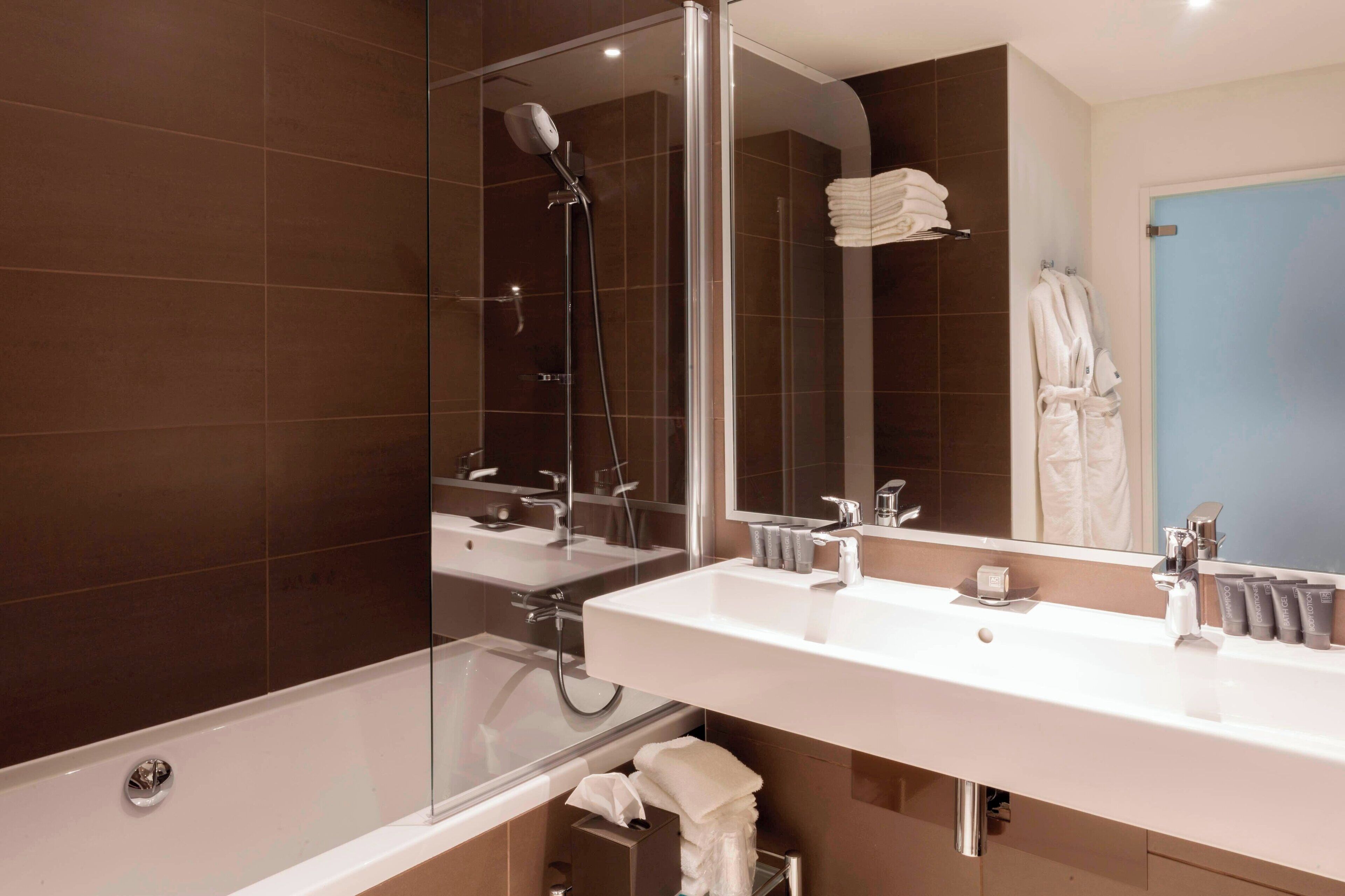 A modern bathroom with a glass-enclosed shower, dual sinks, and a large mirror.