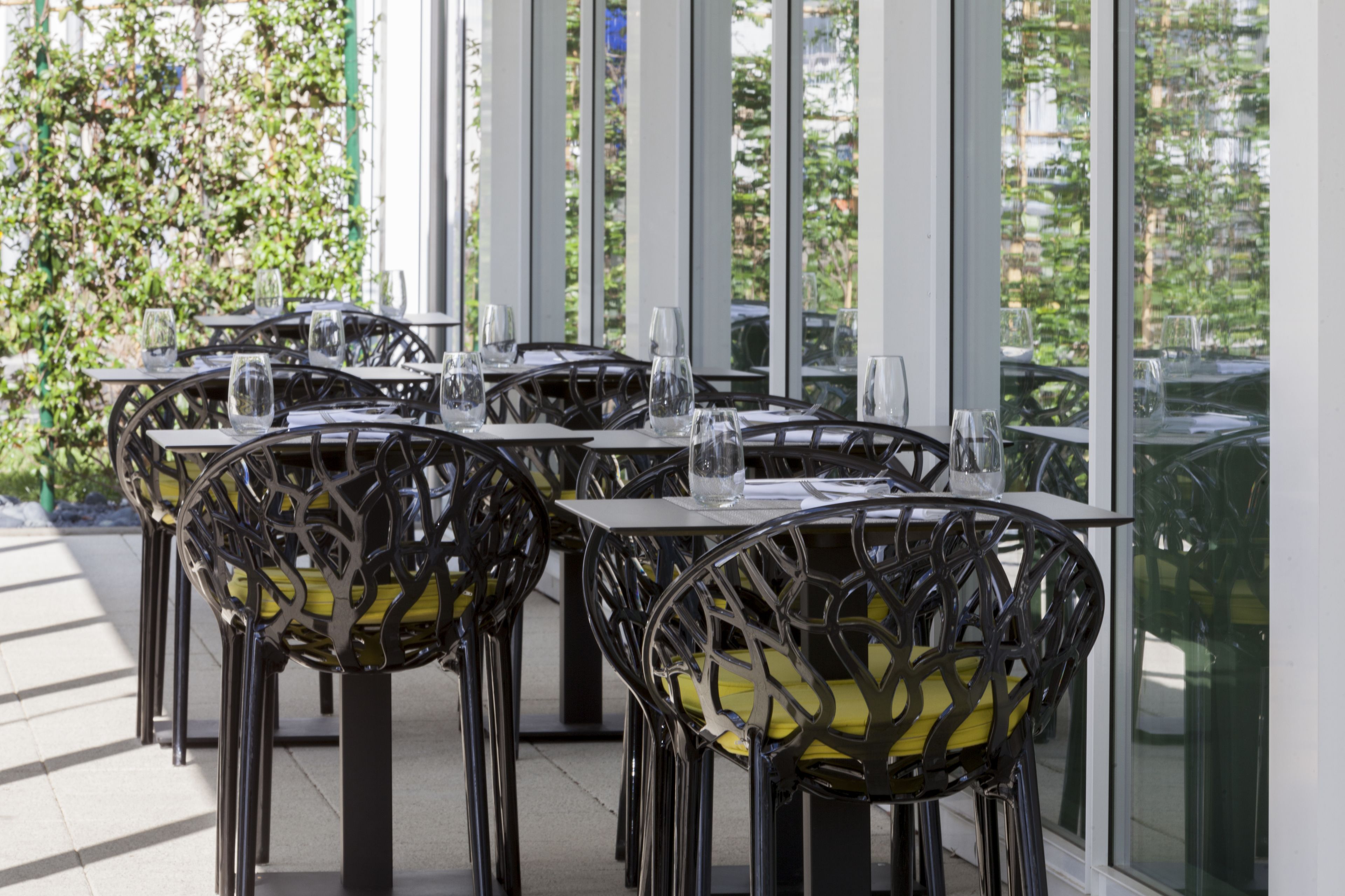 A restaurant with outdoor seating, featuring tables and chairs with a modern design.