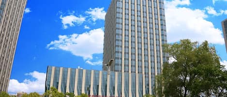 A tall, modern building with a clear sky and clouds.