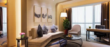 Una habitación de hotel moderna con sofá, sillones, una mesa de comedor y obras de arte en las paredes.