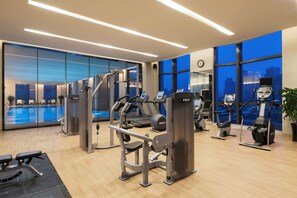A gym with exercise equipment, a pool, and large windows with a city view. - Wanda Realm Bengbu (Bengbu)