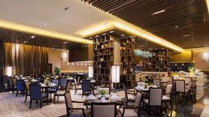 Un comedor amplio con varias mesas y sillas, una zona de bar central y estanterías decorativas con objetos.