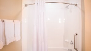 A shower area with a glass door, a towel rack with towels, and a handrail. - Holiday Inn Express Wichita South by IHG (Wichita)