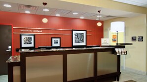 A reception desk with framed pictures, a "welcome to richland" sign, and a "Hilton Honors" sign. - Hampton Inn Richland (Richland)