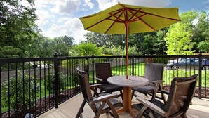 A covered outdoor seating area with a round table and four chairs, surrounded by a black metal fence. - Hampton Inn Richland (Richland)