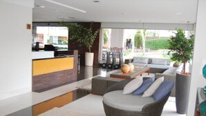 Una hall moderna con reception, zona salotto e ampie finestre.