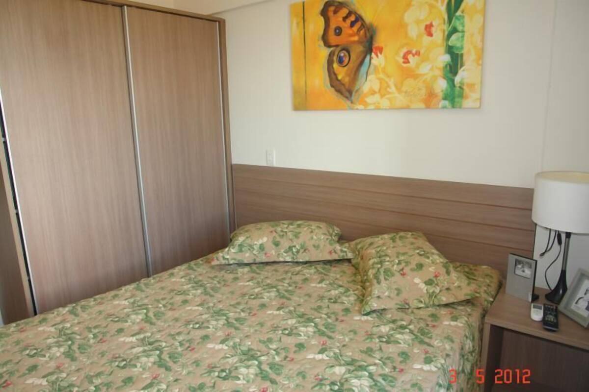 A bedroom with a bed, a nightstand, a lamp, and a painting on the wall.