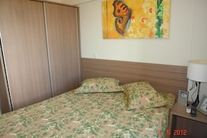 A bedroom with a bed, a nightstand, a lamp, and a painting on the wall.