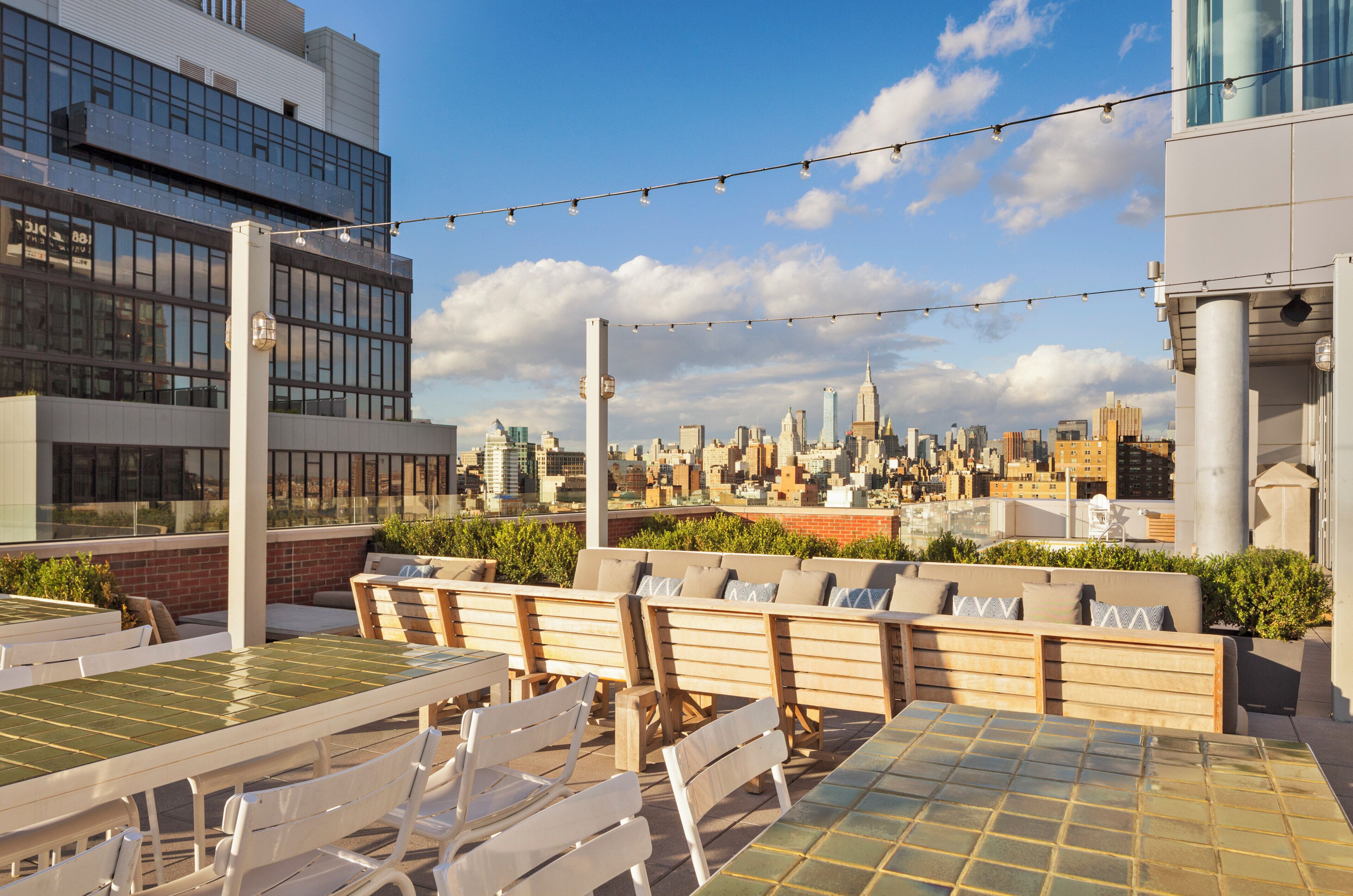 A rooftop terrace with outdoor seating and a city skyline view.