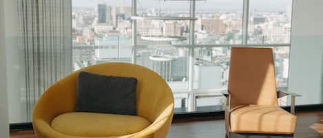 Una habitación moderna con un ventanal grande, una silla amarilla y una silla marrón.