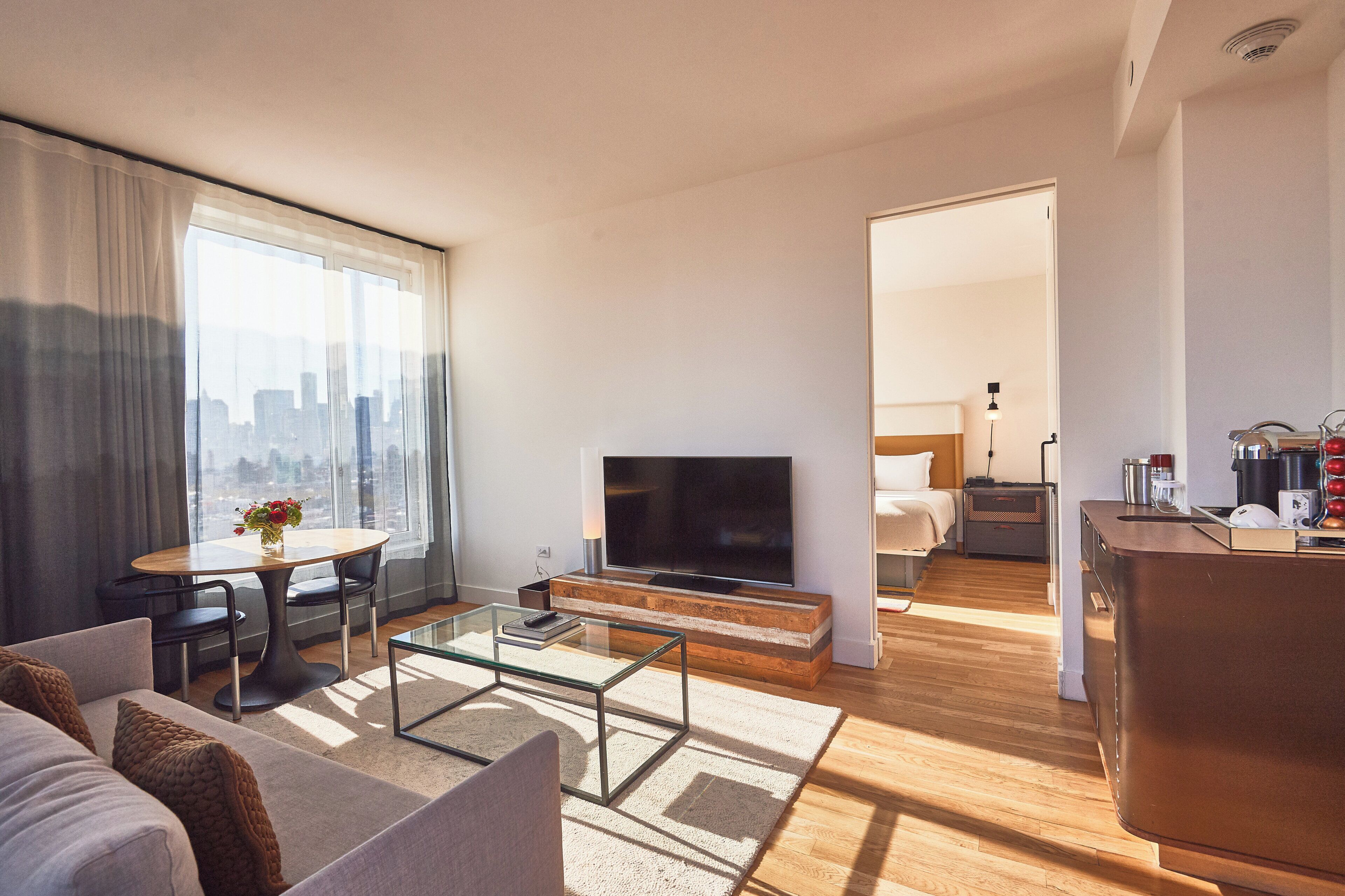 Een moderne woonkamer met een bank, salontafel, televisie en uitzicht op de stad.
