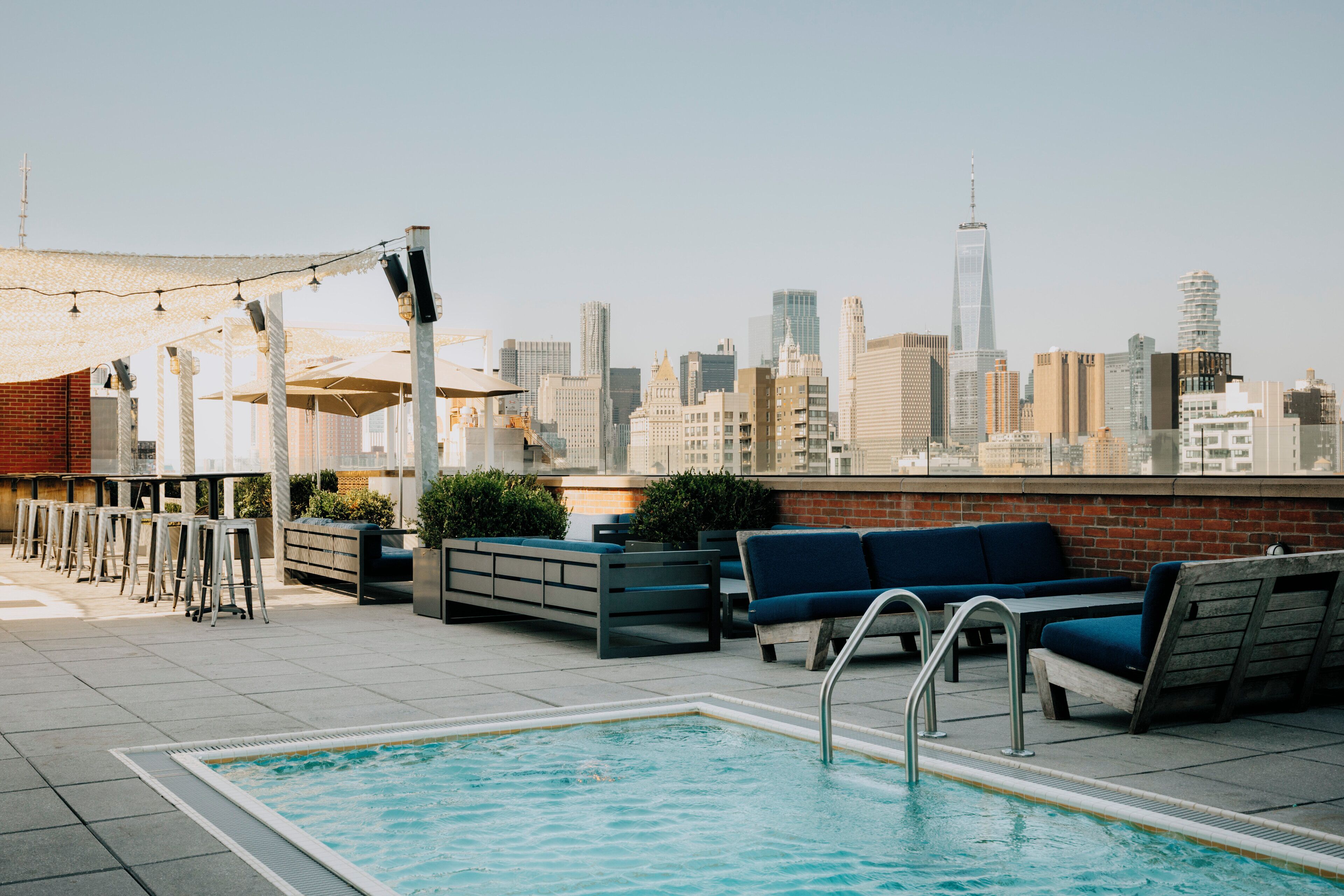 Uma área de piscina no terraço com assentos e vista para o horizonte urbano.