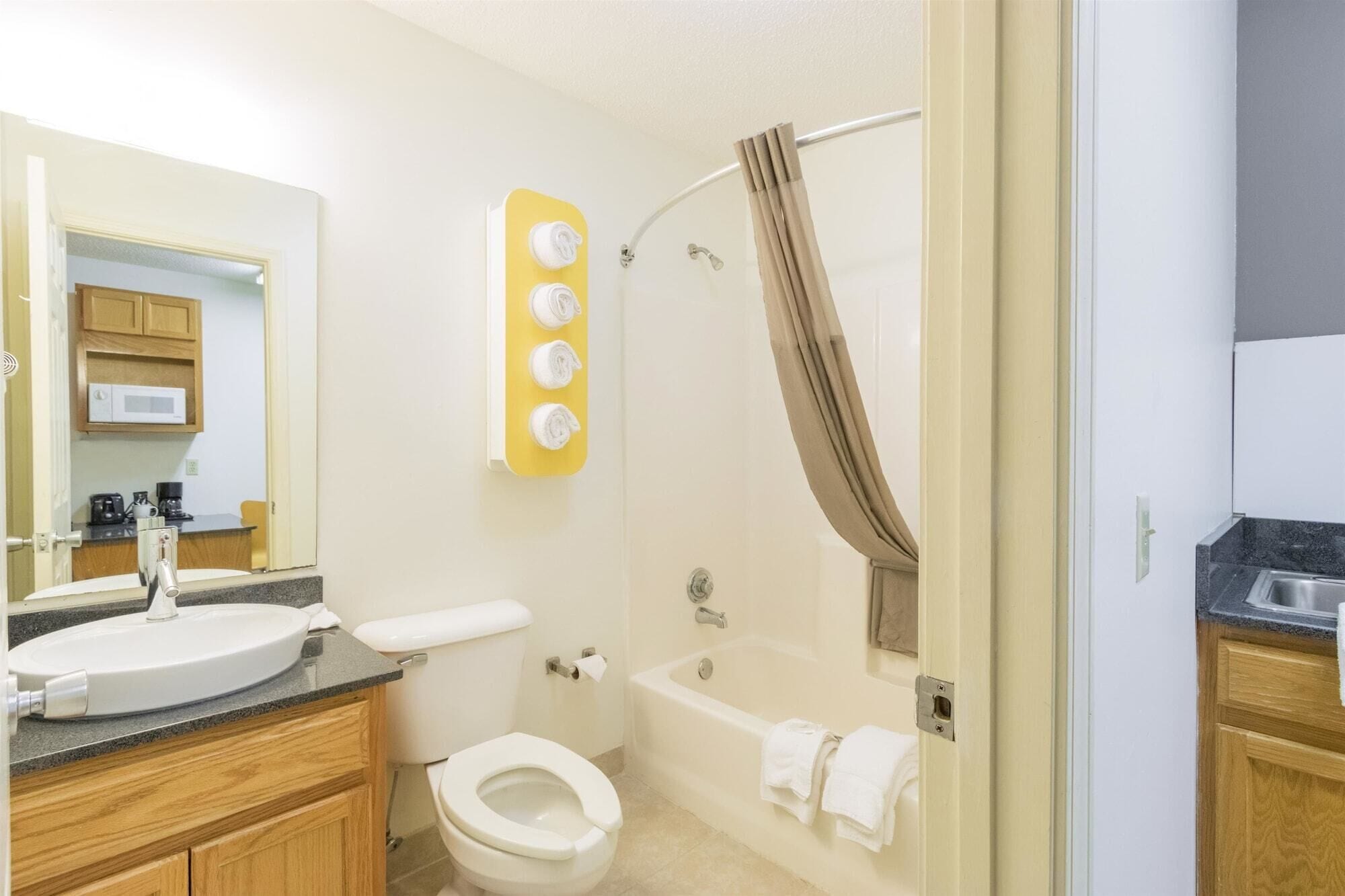 A bathroom with a toilet, sink, and bathtub. There is a shower curtain and a towel rack with towels.