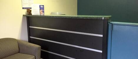 A reception desk with a dark-colored counter and a patterned sofa to the left.