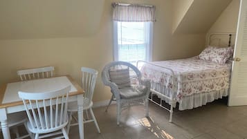 A bedroom with a bed, a chair, a table, and a window.