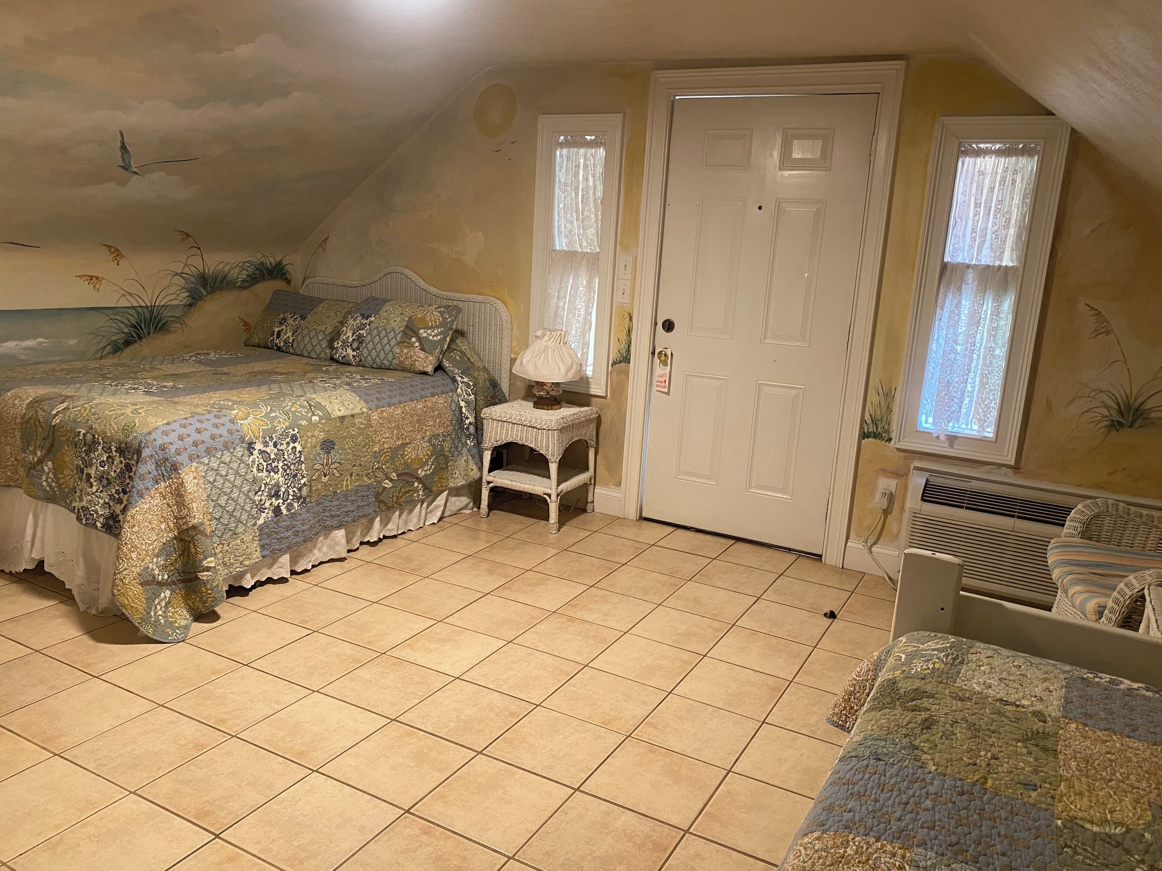 A bedroom with a bed, a nightstand, a door, and a window.