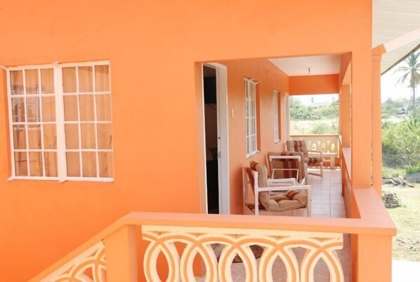 A bright orange building with a covered outdoor seating area and a staircase.