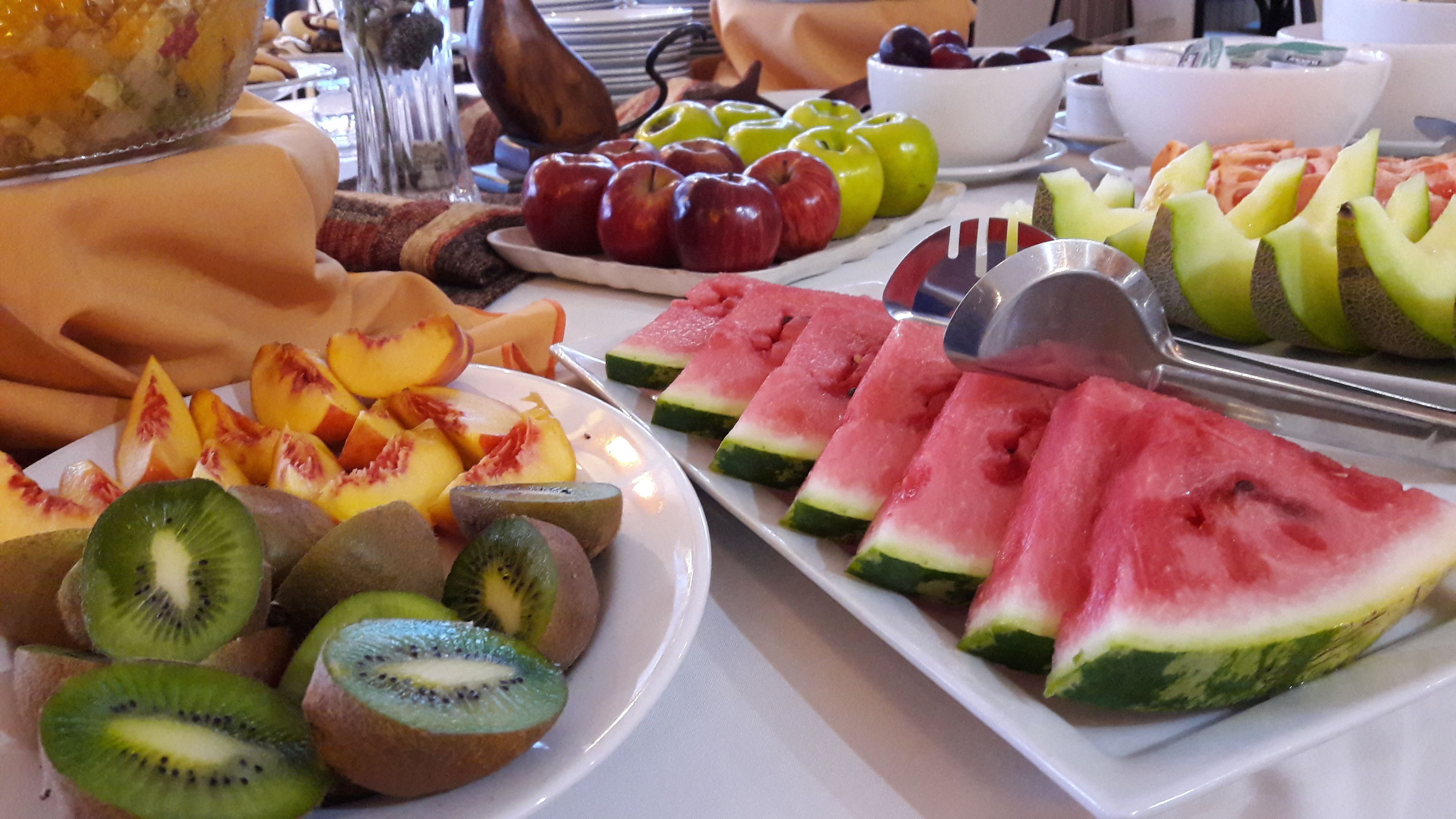 Un buffet proposant une variété de fruits et de légumes, notamment des pommes en tranches, de la pastèque et des kiwis.