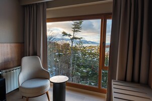 Una habitación con un ventanal grande, una silla, una mesita y un radiador.