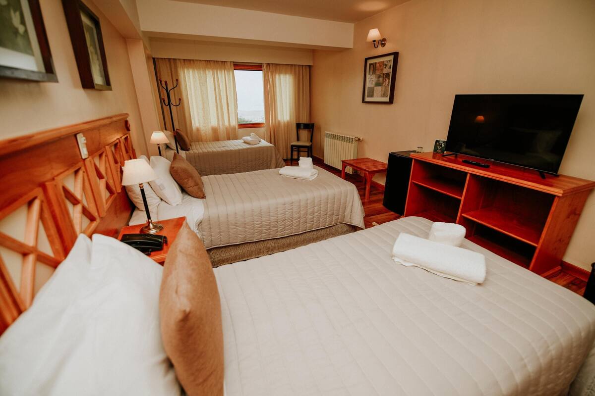 Une chambre d’hôtel avec deux lits, une télévision, une petite table et une chaise.