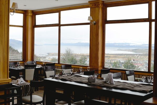 A dining area with large windows offering a scenic view of a lake and mountains.
